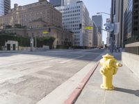 an empty city street in the daytime with a building on both sides of it and a yellow fire hydrant on the other side