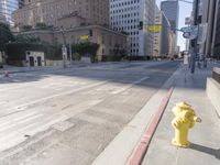 an empty city street in the daytime with a building on both sides of it and a yellow fire hydrant on the other side