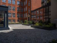 several plants sit in decorative concrete planters along the sidewalk of a building that is very modern