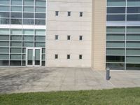 large white building with several windows on top of it, next to a sidewalk with grass, and an empty parking meter