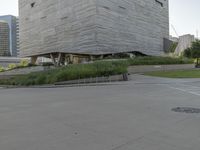 a street sign next to the building and ramp near the grass area of the building