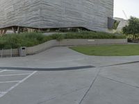 a street sign next to the building and ramp near the grass area of the building