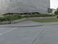 a street sign next to the building and ramp near the grass area of the building