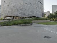 a street sign next to the building and ramp near the grass area of the building