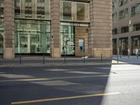 a couple walks on the sidewalk in front of a glass building and traffic cones in downtown minneapolis