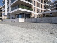 an empty concrete parking lot next to some buildings on the hillside side with several windows