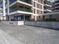 an empty concrete parking lot next to some buildings on the hillside side with several windows