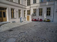 an empty parking lot with plants in the ground and on the side of the building, there is an enclosed area and windows