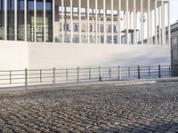 a woman walking in a long walkway near the waterfront on a sunny day near a large white building