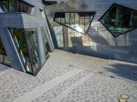 the two buildings have many windows and some benches outside them and sidewalks underneath them