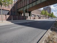 a street under a bridge that is over some cars going under it's bridge