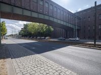 a street under a bridge that is over some cars going under it's bridge