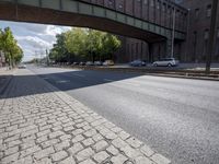 a street under a bridge that is over some cars going under it's bridge