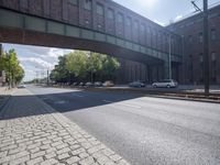 a street under a bridge that is over some cars going under it's bridge