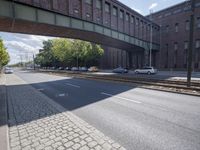 a street under a bridge that is over some cars going under it's bridge