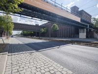 a street under a bridge that is over some cars going under it's bridge