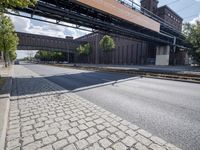 a street under a bridge that is over some cars going under it's bridge