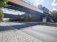 a street under a bridge that is over some cars going under it's bridge