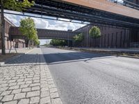 a street under a bridge that is over some cars going under it's bridge