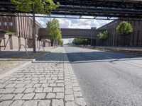 a street under a bridge that is over some cars going under it's bridge