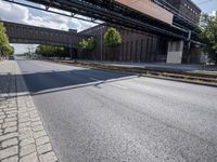 a street under a bridge that is over some cars going under it's bridge