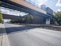 a street under a bridge that is over some cars going under it's bridge