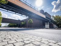 a street under a bridge that is over some cars going under it's bridge