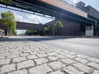 a street under a bridge that is over some cars going under it's bridge