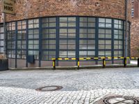 a red brick building with a metal bench on the side of it and a yellow gate