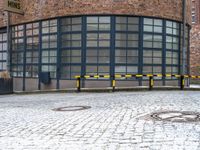 a red brick building with a metal bench on the side of it and a yellow gate