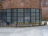 a red brick building with a metal bench on the side of it and a yellow gate