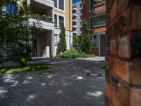 a residential driveway with a bench and bushes in between buildings and green grass on either side