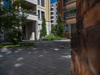 a residential driveway with a bench and bushes in between buildings and green grass on either side