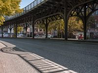 a street is filled with parked cars, and a bridge spans over it on the other side