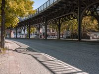 a street is filled with parked cars, and a bridge spans over it on the other side