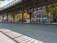 a street is filled with parked cars, and a bridge spans over it on the other side