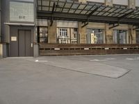 an empty building with signs on the street and people on bikes in traffic passing by