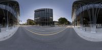 a 360 view of a big street next to buildings and street lamps with a large glass building in the background