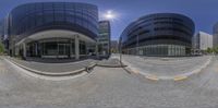 a street corner and a wide lens fish eye view of a building that is very tall and has several windows