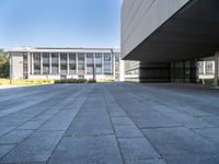 an empty concrete pavement with building in the background, outside view, from sidewalk level