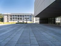 an empty concrete pavement with building in the background, outside view, from sidewalk level