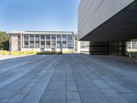 an empty concrete pavement with building in the background, outside view, from sidewalk level