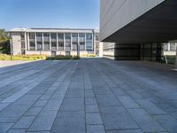 an empty concrete pavement with building in the background, outside view, from sidewalk level