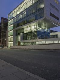 a modern building sits empty near a street at night with the lights on and no people in