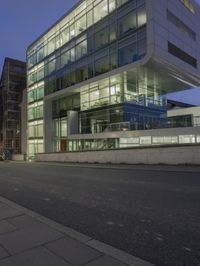 a modern building sits empty near a street at night with the lights on and no people in
