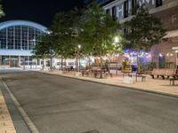 a street with many tables and chairs on both sides of the road at night by the city center