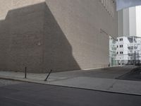 a large brown building in the middle of some buildings by a street corner and several parked cars