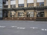 an empty building with signs on the street and people on bikes in traffic passing by