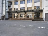 an empty building with signs on the street and people on bikes in traffic passing by