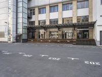 an empty building with signs on the street and people on bikes in traffic passing by